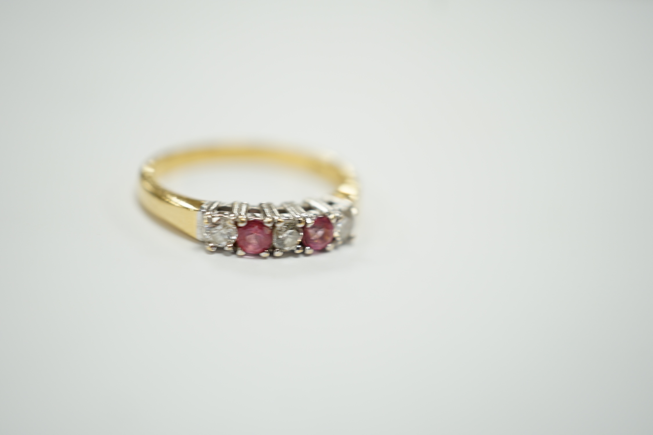 An 18ct gold, two stone pink sapphire? and three stone diamond set half hoop ring, size O, gross weight 3.3 grams.